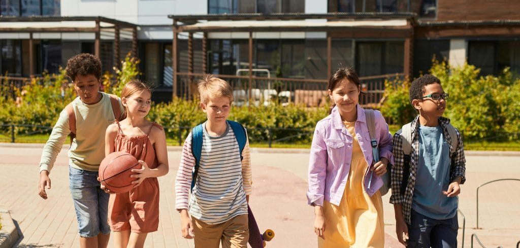 Group of children walking in school courtyard.