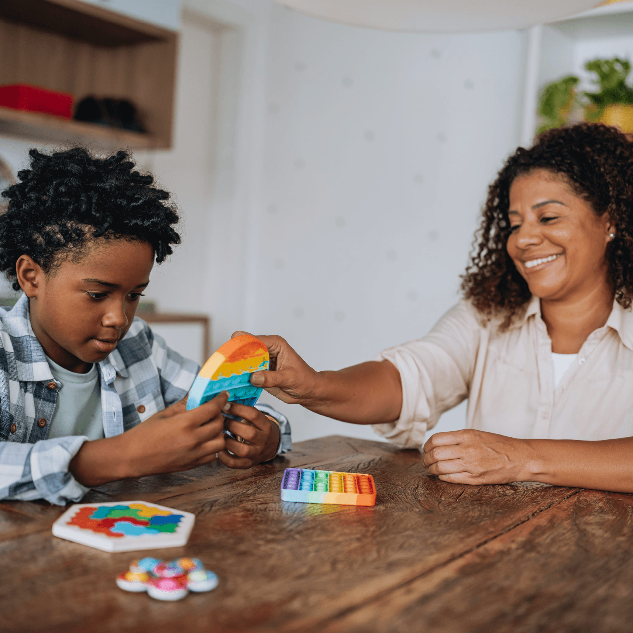 Woman and young boy at table playing with fidget toys.