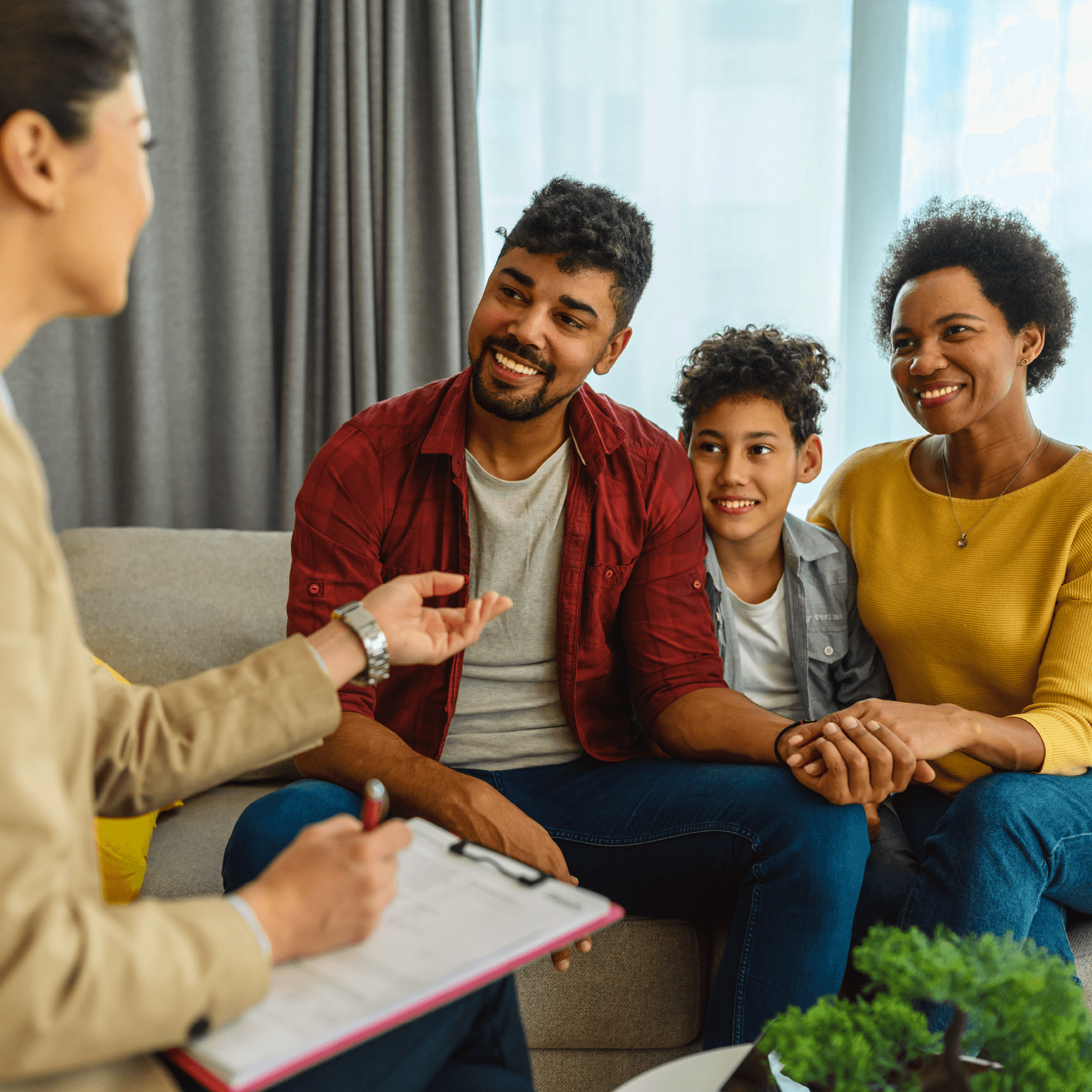 Family with father, son and mother sitting on couch across from woman in a family support-type session.