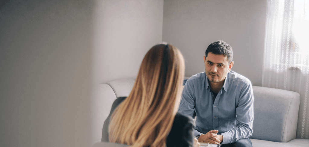 Man sitting on couch across from female counsellor.